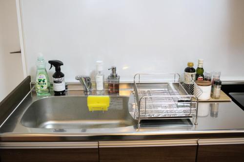 a kitchen sink with a dish rack next to it at Guest room MINAMI 沖縄 in Okinawa City