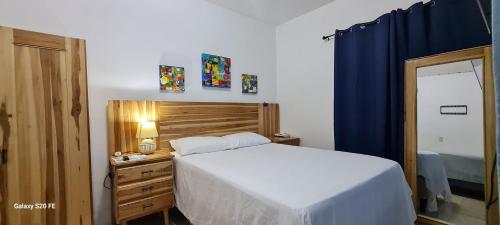 1 dormitorio con cama blanca y cortina azul en Apart Eco Estudio Joocah en Trujillo