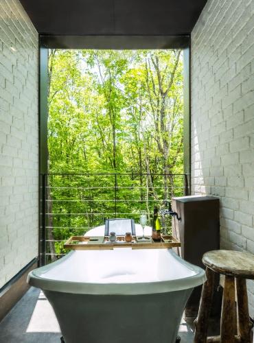 a bath tub in a room with a large window at Shelter Garden Nikko in Nikko
