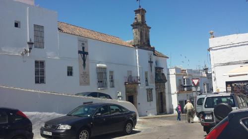 a city street with cars parked in front of a white building at Hostal Cuesta de Belén in Arcos de la Frontera