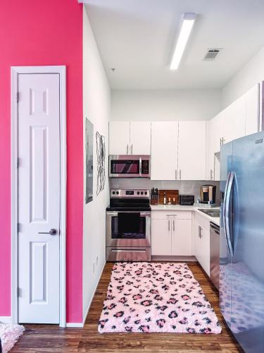 a kitchen with white cabinets and a pink wall at Dolly's Glam Getaway - Glittering Gem Near Broadway in Nashville