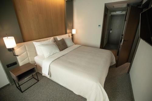 a bedroom with a large white bed and a lamp at The Hunter's Lodge Kamnik in Skopje