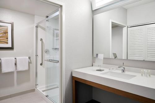 a white bathroom with a sink and a shower at Courtyard Milwaukee Downtown in Milwaukee
