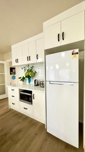 a kitchen with white cabinets and a refrigerator at Steam Land Stay in Rotorua