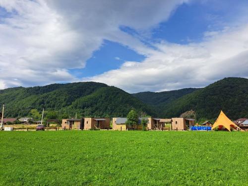 ein grünes Feld mit Häusern und Bergen im Hintergrund in der Unterkunft REST 360 in Scheschory
