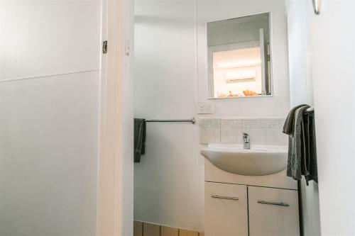 ein Bad mit einem Waschbecken und einem Spiegel in der Unterkunft Alpine Riverside Cottages in Porepunkah