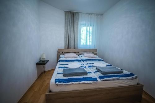 a bedroom with a bed with two pillows on it at Apartman Garden in Cserkeszőlő