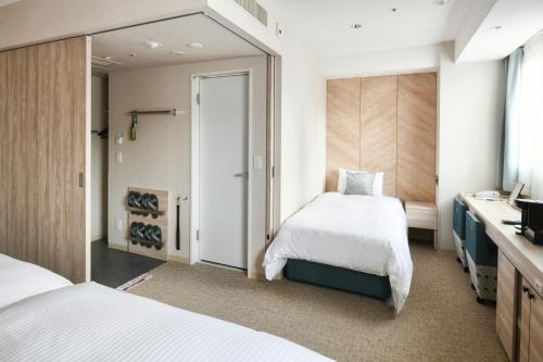 a hotel room with two beds and a television at Vessel Hotel Campana Nagoya in Nagoya