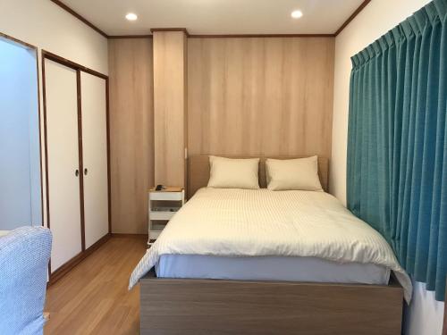 a bedroom with a large bed with a blue curtain at 大阪長居港湾客房 in Osaka