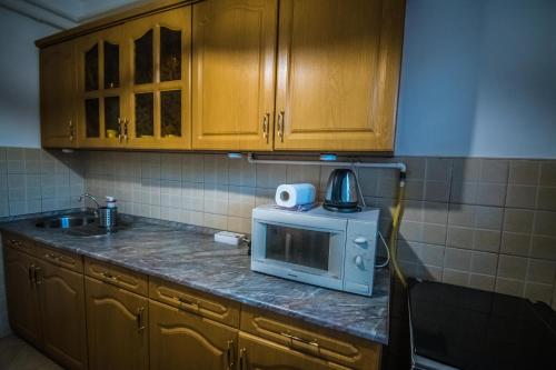 a kitchen with wooden cabinets and a microwave on a counter at Főtér Apartman in Szarvas