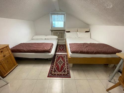 two beds in a small room with a rug at Comfortable apartment in commercial centre in Unterhaching