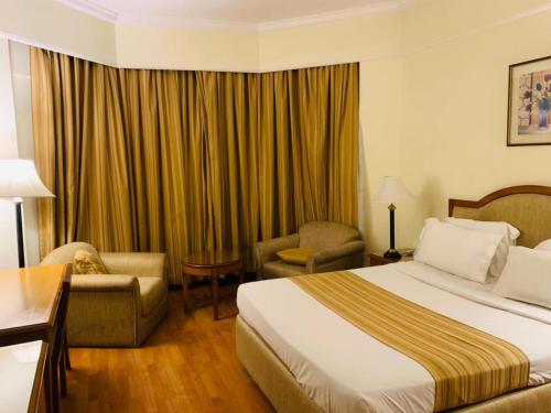 a hotel room with a bed and a chair at Katriya Hotel and Tower in Hyderabad