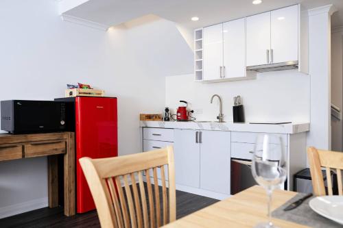a kitchen with white cabinets and a red refrigerator at Salamanca Getaway Battery Point in Hobart