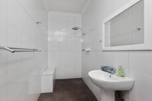 uma casa de banho branca com um lavatório e um espelho em Luxury Abode, family heaven em Paraparap