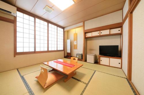 a living room with a table and a tv at Hotel Pony Onsen in Towada