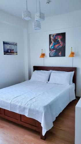 a bedroom with a large bed with white sheets at Cozy almond drive condo in cebu in Talisay