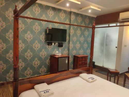 a bedroom with a bed and a tv on a wall at Zoom Inn Heritage in Puducherry