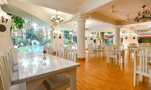 a dining room with tables and chairs and a pool at Hotel Toro Highland Beach Resort With Pool - 500M From Candolim Beach in Candolim