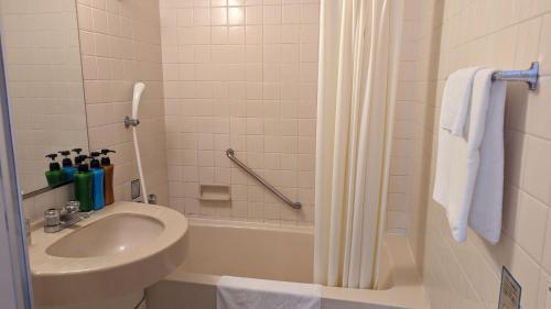 a white bathroom with a sink and a shower at 小牧シティホテル in Komaki