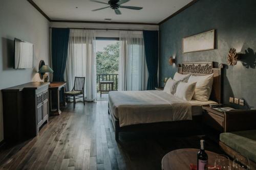 a bedroom with a bed and a couch and a window at Amour Resort Bavi in Hanoi