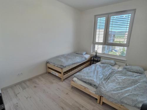 two twin beds in a room with a window at FREE 2X parking and free Wifi NEW Suncatcher apartment in Bratislava