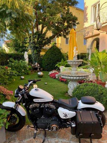a motorcycle parked in front of a garden with a fountain at Villa Auguste in Pörtschach am Wörthersee