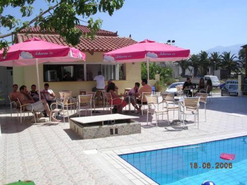 a group of people sitting at a table with pink umbrellas at Eleni Palace in Amoudara Herakliou