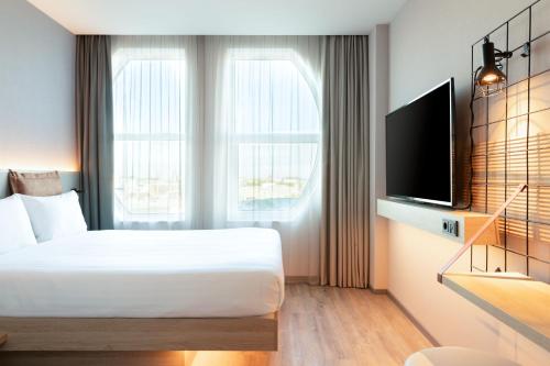 Schlafzimmer mit einem Bett und einem Flachbild-TV in der Unterkunft Moxy The Hague in Den Haag