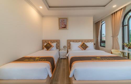 two beds in a room with two windows at BẢO DUY HOTEL 5 in Da Lat