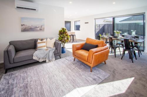 a living room with a couch and a chair at Sunsoaked & Stylish 3 Bed, 1.5 Bath Home w Garage in Christchurch