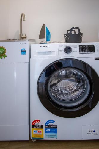 a white washing machine sitting next to a dryer at Sunsoaked & Stylish 3 Bed, 1.5 Bath Home w Garage in Christchurch