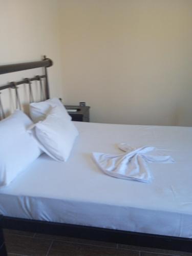 uma cama branca com lençóis e almofadas brancos em Golden village em Astakos
