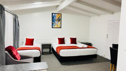two beds with red pillows in a room at 18th Avenue Thermal Motel in Tauranga