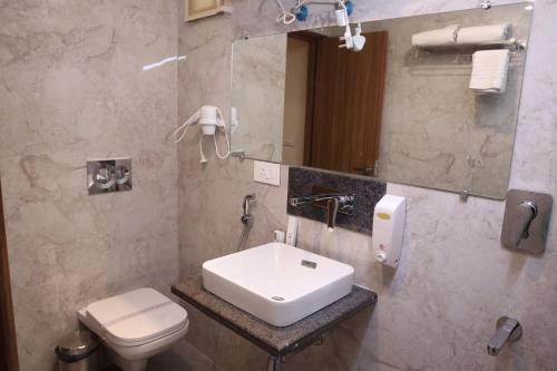 a bathroom with a sink and a toilet and a mirror at Hotel Sharda Residency in Patna