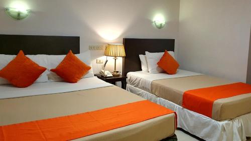 a hotel room with two beds with orange pillows at A Hotel Baguio in Baguio