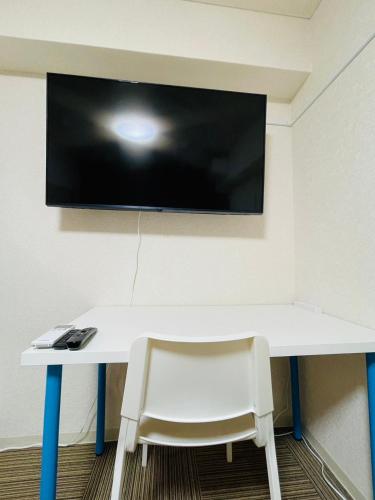 una scrivania bianca con sedia e una televisione appesa a un muro di DAIKAN YOKOSUKA l 横須賀中央 a Kusugaurachō