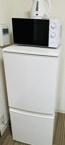 um micro-ondas sentado em cima de um frigorífico branco em DAIKAN YOKOSUKA l 横須賀中央 em Kusugaurachō