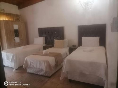 a hotel room with two beds with white sheets at El Rose Guest House in Rustenburg