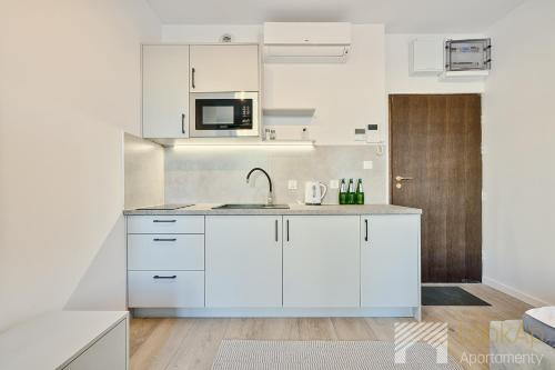 a kitchen with white cabinets and a sink at Polonia Residence III by LookAp Parking in Łódź