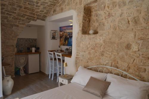 a bedroom with a stone wall with a bed and a kitchen at Geometric Donna Giulia in Casamassima