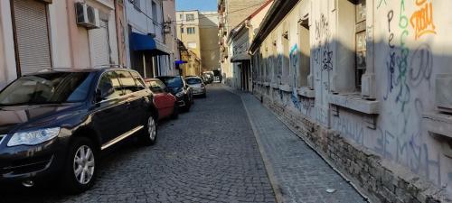 a street with cars parked next to a wall with graffiti at River Hostel Belgrade in Belgrade