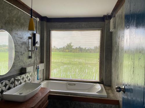 La salle de bains est pourvue d'une baignoire, d'un lavabo et d'une fenêtre. dans l'établissement บ้านวิวนา Baan View Na, à Ban Mae Cho
