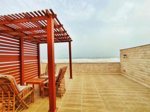 a wooden pergola with chairs and a table on the beach at SEA VILLAS Salalah in Salalah