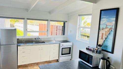 a kitchen with a sink and a refrigerator and windows at 18th Avenue Thermal Motel in Tauranga