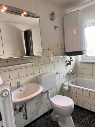 een badkamer met een toilet, een wastafel en een bad bij Gäste-, Handwerkerzimmer in Rosenfeld