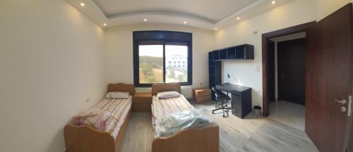 a room with two beds and a desk and a window at Perfect view garden in Amman