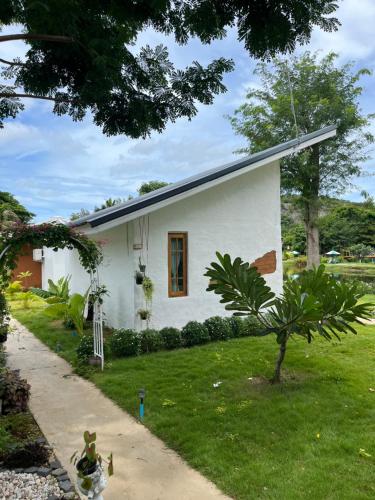 een klein wit huis met een grasveld bij The Little Clay House (Huahin) in Ban Thap Tai (1)