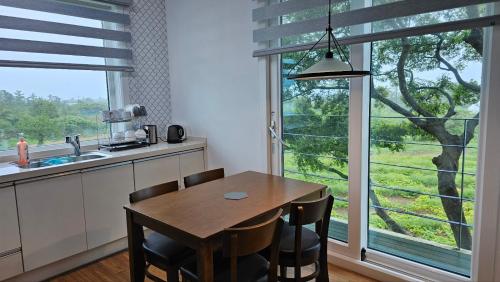 a kitchen with a table and chairs and a large window at Bibidoongdoong in Jeju