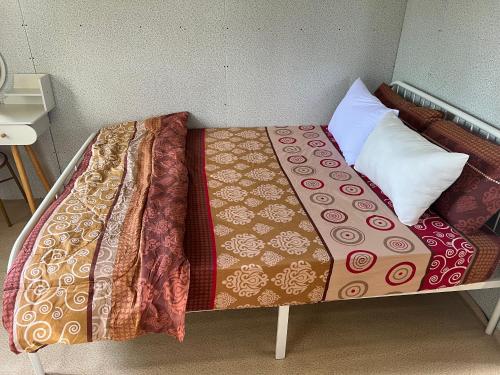 a bed with a blanket and pillows on it at Safiyya Homestay in Kota Bharu