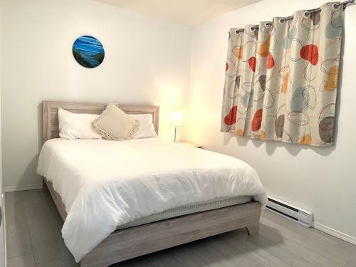 a bedroom with a bed with white sheets and a window at Summer Breeze in Sooke